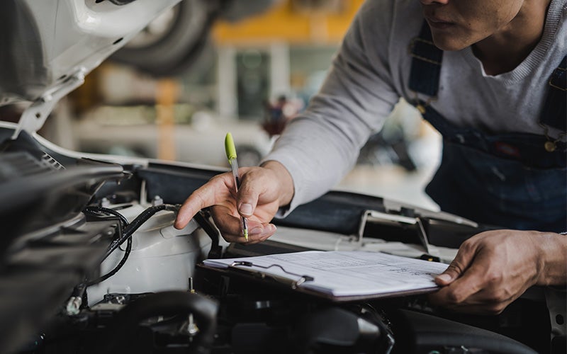 A man inspects the engine of a car, focused on the mechanical components under the hood.