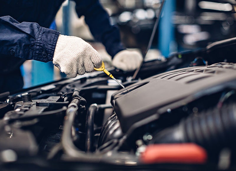 A man in a workshop is focused on repairing a car engine, surrounded by tools and parts.